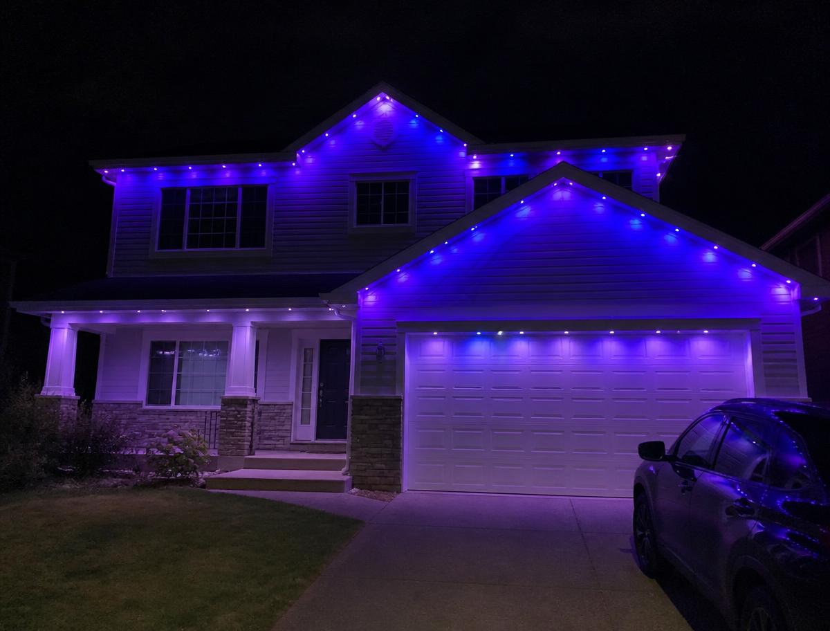 Two-storey home at night with permanent RGB lights glowing blue and purple
