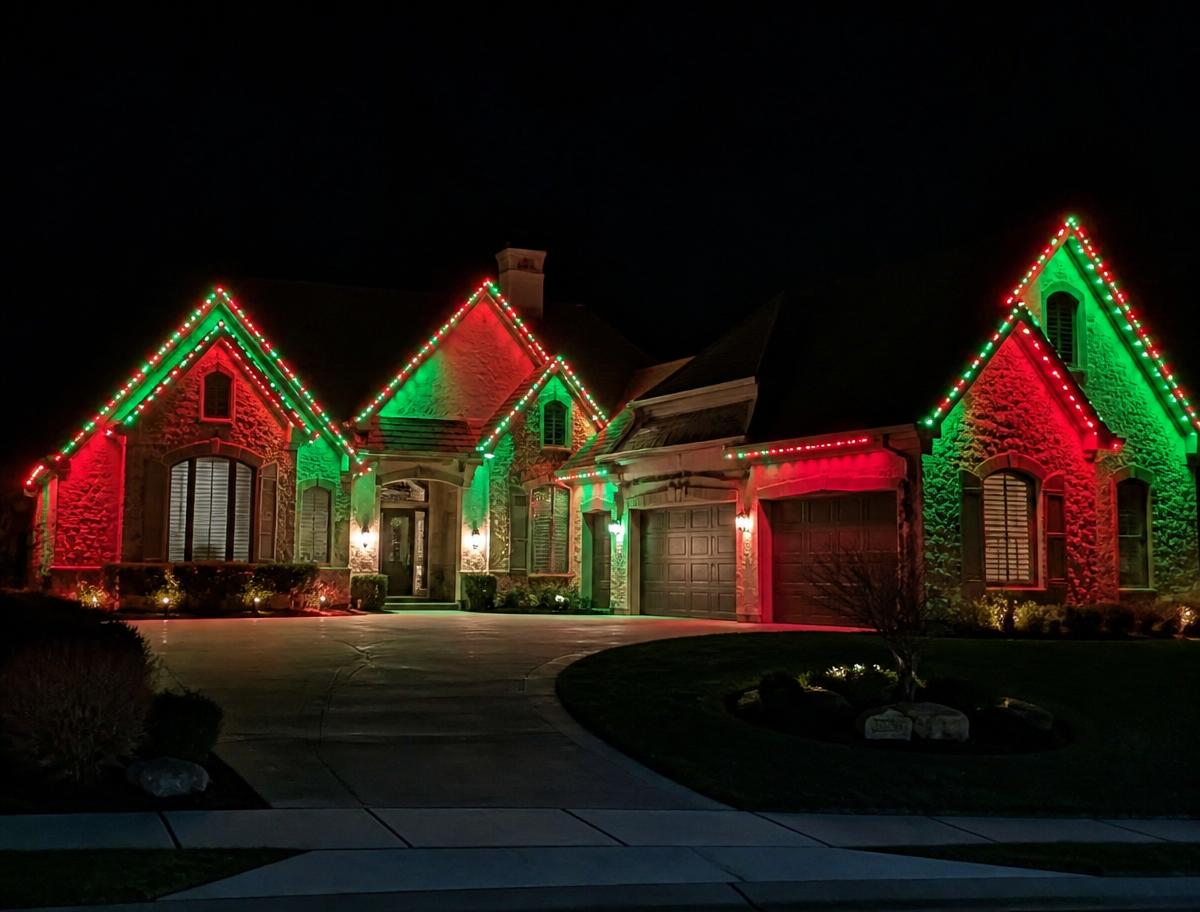 Luxury stone home at night with permanent RGB lights in green and red