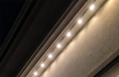 Permanent LED lights receding along a garage soffit, washing the wall in warm light